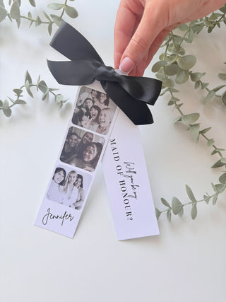 Image of a card with the text 'Will you....be my Bridesmaid?' and a black ribbon, perfect for asking a friend.