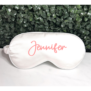 White satin sleep mask with personalized name in elegant script, featuring an adjustable elastic strap for comfort.